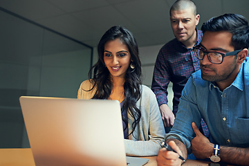 Image showing They know how to handle business like pros. Cropped shot of a group of businesspeople working late on a laptop in an office.