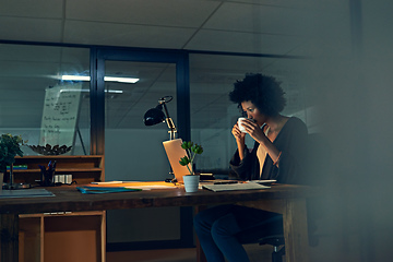 Image showing Shes got a strong cuppa to keep her going. Cropped shot of a young businesswoman working late on a laptop in an office.