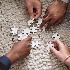 Image showing Pulling together to solve a problem. Cropped shot of a group of people fitting puzzle pieces together.