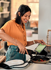 Image showing Olive oil, the good kind of fat. Shot of a happy young woman preparing a healthy meal at home.