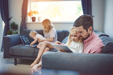 Image showing They keep their home connected. Shot of an adorable little girl using a digital tablet with her father on the sofa at home.