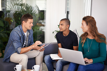 Image showing Brainstorming some ideas. A team of young business professionals using technology in an informal meeting.