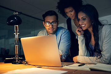 Image showing Theyre all equally committed to accomplishing their deadlines. Cropped shot of a group of businesspeople working late on a laptop in an office.