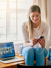 Image showing Choosing some tunes for her next study session. Shot of a young woman using her smartphone while sitting on her desk at home.