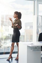 Image showing Be bold and stand out above the rest. Full length shot of a young businesswoman standing in her office and busy talking on a smartphone.