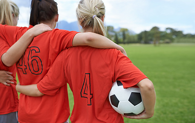 Image showing Ready to take on the field. A girls soccer team standing with their arms around each others shoulders looking towards the field.