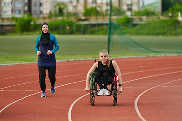 Image showing A Muslim woman in a burqa running together with a woman in a wheelchair on the marathon course, preparing for future competitions.