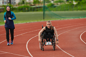 Image showing A Muslim woman in a burqa running together with a woman in a wheelchair on the marathon course, preparing for future competitions.