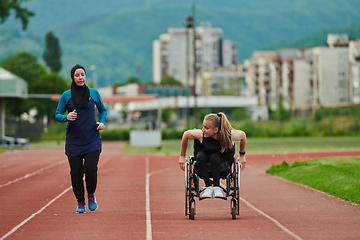 Image showing A Muslim woman in a burqa running together with a woman in a wheelchair on the marathon course, preparing for future competitions.