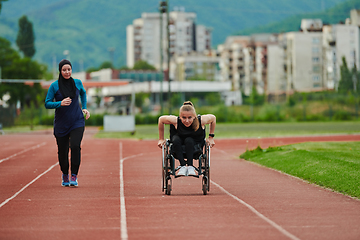 Image showing A Muslim woman in a burqa running together with a woman in a wheelchair on the marathon course, preparing for future competitions.