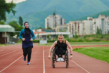 Image showing A Muslim woman in a burqa running together with a woman in a wheelchair on the marathon course, preparing for future competitions.