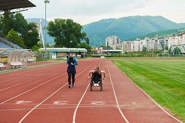 Image showing A Muslim woman in a burqa running together with a woman in a wheelchair on the marathon course, preparing for future competitions.