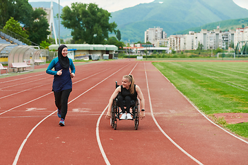 Image showing A Muslim woman in a burqa running together with a woman in a wheelchair on the marathon course, preparing for future competitions.