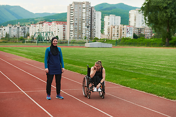 Image showing A Muslim woman in a burqa running together with a woman in a wheelchair on the marathon course, preparing for future competitions.