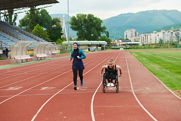 Image showing A Muslim woman in a burqa running together with a woman in a wheelchair on the marathon course, preparing for future competitions.