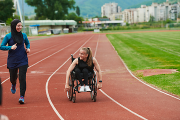 Image showing A Muslim woman in a burqa running together with a woman in a wheelchair on the marathon course, preparing for future competitions.