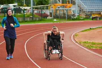 Image showing A Muslim woman in a burqa running together with a woman in a wheelchair on the marathon course, preparing for future competitions.