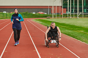 Image showing A Muslim woman in a burqa running together with a woman in a wheelchair on the marathon course, preparing for future competitions.