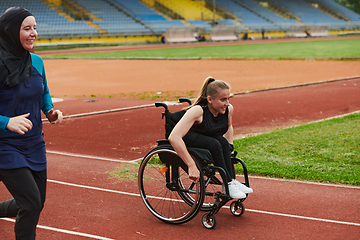 Image showing A Muslim woman in a burqa running together with a woman in a wheelchair on the marathon course, preparing for future competitions.