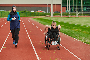 Image showing A Muslim woman in a burqa running together with a woman in a wheelchair on the marathon course, preparing for future competitions.