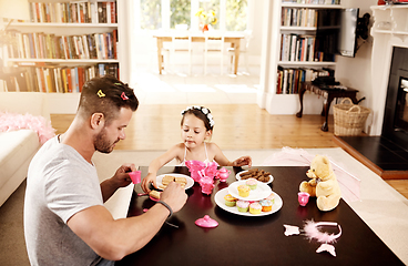 Image showing Heres a cookie for you too Dad. Shot of a father and his little daughter having a tea party together at home.