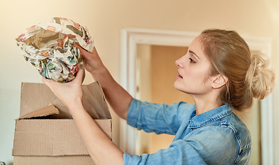 Image showing Making sure her valuables are snugly packed. Shot of a young woman unpacking a box at home.