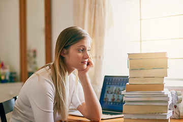 Image showing Thats an overwhelming amount of information. Shot of a young woman looking overwhelmed by the pile of books on her desk.