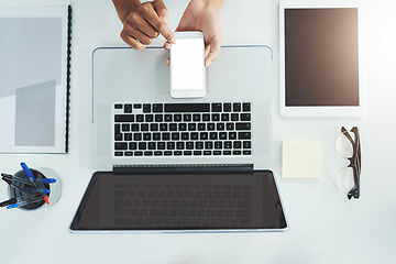 Image showing Staying in the loop with the touch of a button. High angle shot of an unrecognizable woman sitting at her office desk scrolling through her smartphone.