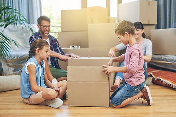 Image showing Their familys got moving day covered. Shot of a family of four helping each other pack boxes on moving day.