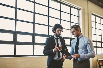 Image showing I think youre off to a good start. Shot of two well-dressed businessmen brainstorming together over a tablet in their office.