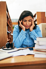 Image showing I wont let this headache stop me from my studies. Shot of a university student looking stressed out while working in the library at campus.