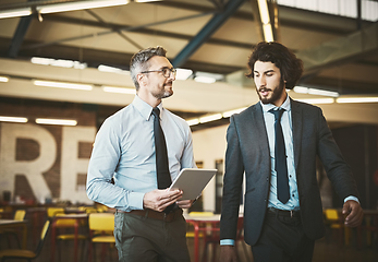 Image showing On their way to present a great idea. Shot of two well-dressed businessmen brainstorming together over a tablet in their office.