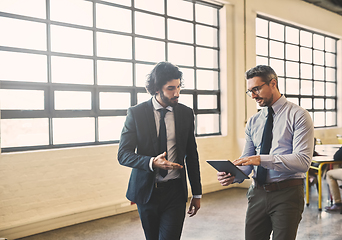 Image showing Wireless technology keeps their business moving forward. Shot of two well-dressed businessmen brainstorming together over a tablet in their office.