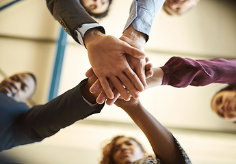 Image showing Brought together by business. Low angle shot of a team of businesspeople piling their hands on top of each other in the office.