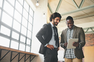 Image showing Check out this cool app I found. Shot of two well-dressed businessmen brainstorming together over a tablet in their office.