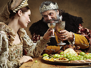 Image showing Maybe a full goblet will cheer you up mlady. A mature king feasting alone in a banquet hall.