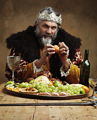 Image showing Its good to be the king. A mature king feasting alone in a banquet hall.