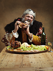 Image showing Ruling is hungry business. A mature king feasting alone in a banquet hall.