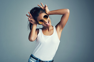 Image showing Showing off her quirky side. Studio portrait of a beautiful young woman gesturing with bunny ears against a grey background.