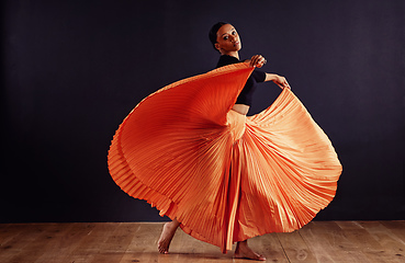 Image showing Exotic expression. Female contemporary dancer in a dramatic pose against dark background.