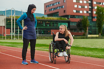 Image showing A Muslim woman wearing a burqa resting with a woman with disability after a hard training session on the marathon course