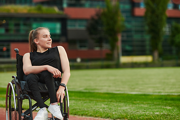 Image showing A smiling woman with disablitiy sitting in a wheelchair and resting on the marathon track after training