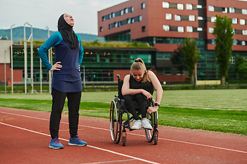 Image showing A Muslim woman wearing a burqa resting with a woman with disability after a hard training session on the marathon course