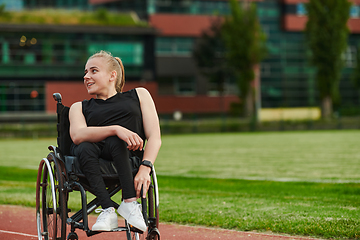 Image showing A smiling woman with disablitiy sitting in a wheelchair and resting on the marathon track after training