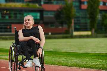 Image showing A smiling woman with disablitiy sitting in a wheelchair and resting on the marathon track after training