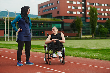 Image showing A Muslim woman wearing a burqa resting with a woman with disability after a hard training session on the marathon course