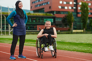 Image showing A Muslim woman wearing a burqa resting with a woman with disability after a hard training session on the marathon course