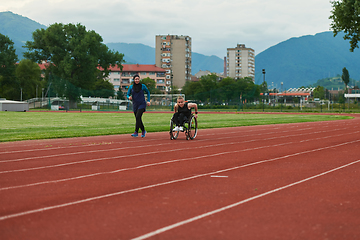 Image showing A Muslim woman in a burqa running together with a woman in a wheelchair on the marathon course, preparing for future competitions.