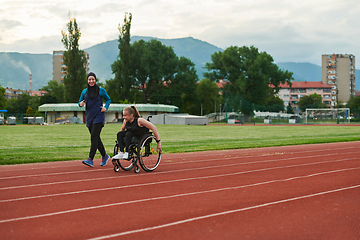 Image showing A Muslim woman in a burqa running together with a woman in a wheelchair on the marathon course, preparing for future competitions.