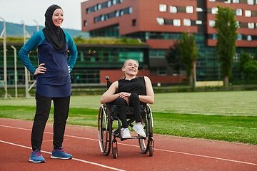 Image showing A Muslim woman wearing a burqa resting with a woman with disability after a hard training session on the marathon course